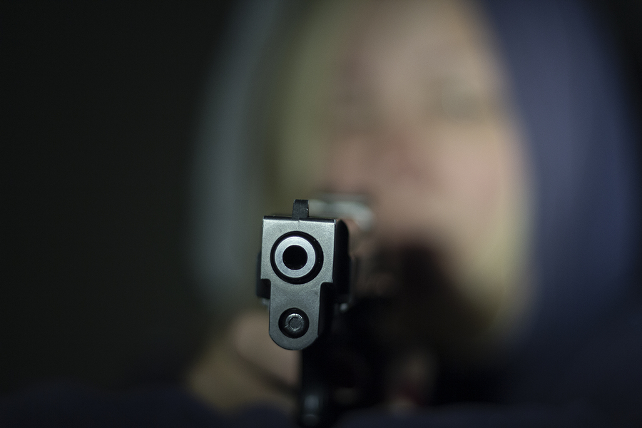 A Woman Holds A Gun In Her Hand And Points It At The Camera . Fo